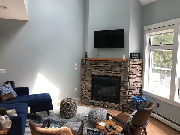 Small television mounted over a stonework fireplace in high-ceiling living room.