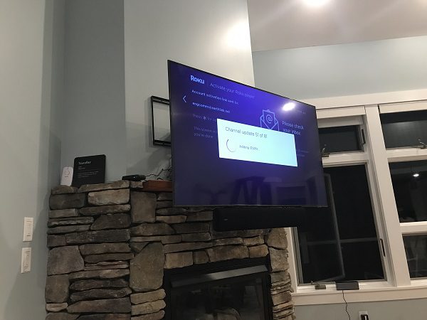 Drop-down TV mount lowering flat screen down to optimal viewing height in front of fireplace.