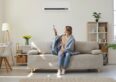 Woman in room turning on HVAC as example of home air quality technology that Schneider Electric and Sendal will be improving with their partnership.
