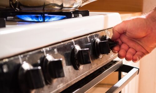 Man turning on gas stoves to emphasize presence of gas appliances and impact on air quality in the home.