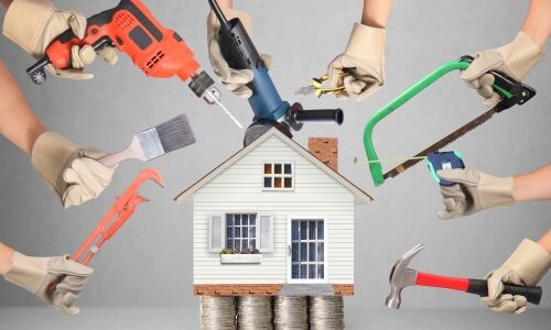 Selection of tools aimed at a house positioned on a stack of money meant to convey home improvement desires against an inflation wracked economy.