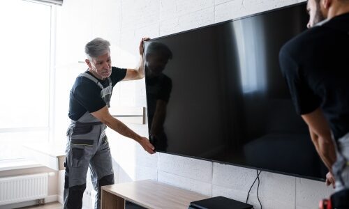 Two men installing a television on the wall