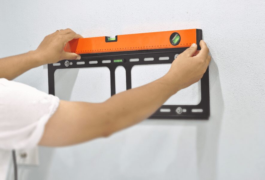 Man measuring the levelness of a TV wall mount.