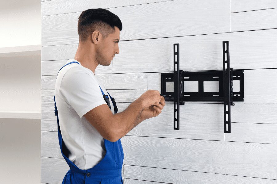 Man screwing in the wall plate for a TV mount.