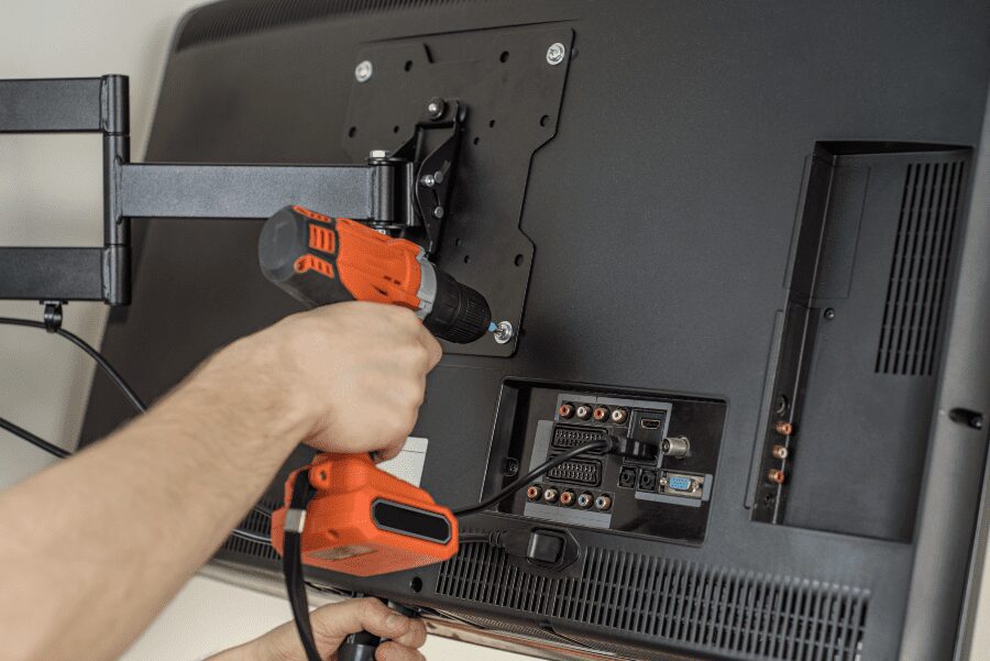 Man affixing mounting bracket onto the back of a flat screen TV.