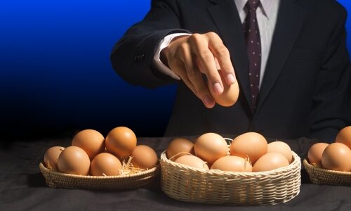 Business portfolio diversification exemplified by man putting many eggs into different baskets.