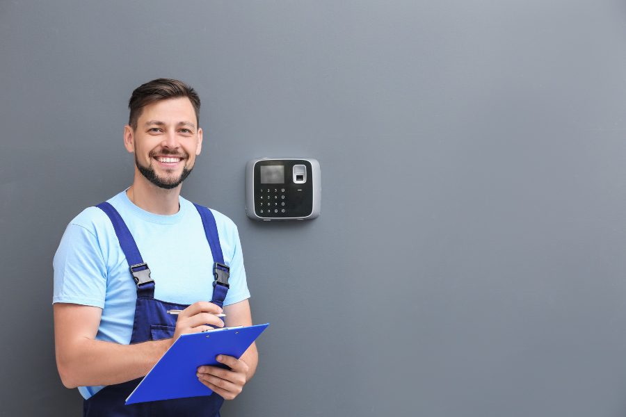 Security systems technician standing in front of installed device.