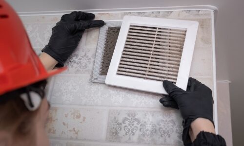 Technician performing maintenance on air conditioning highlighting importance of indoor air quality standards on systems.