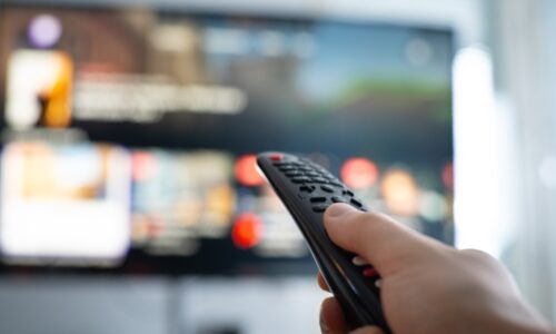 Man with remote control supposedly watching a home video streaming service in a scene meant to represent emerging trends among consumers.