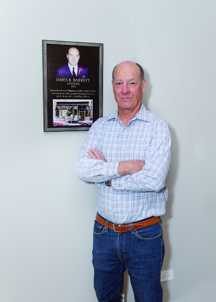 Joe Barrett standing in front of plaque of father who founded Barrett's in 1966.