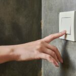 Hand turning on lights meant to emphasize a potential scenario where dirty power can impact lighting quality