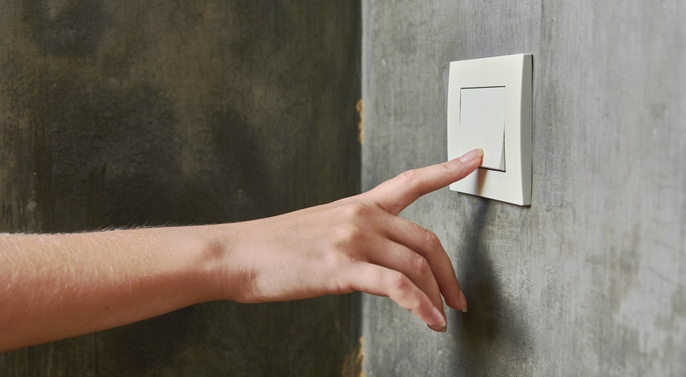 Hand turning on lights meant to emphasize a potential scenario where dirty power can impact lighting quality