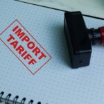 Red Handle Rubber Stamper and Import Tariff text isolated on wooden background