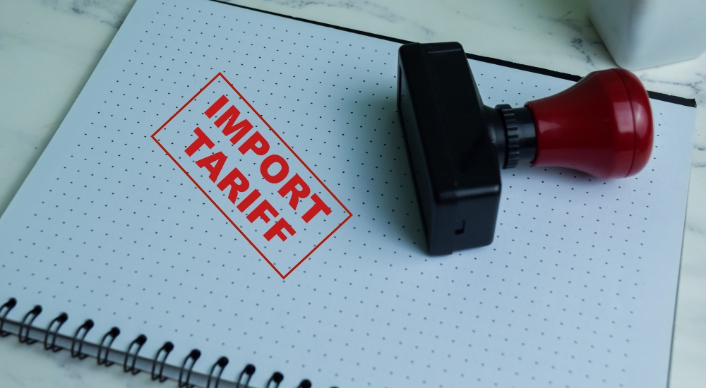 Red Handle Rubber Stamper and Import Tariff text isolated on wooden background