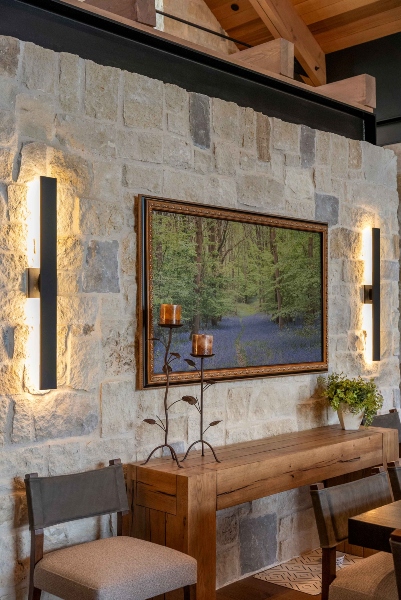 Luxury Colorado home interior showcasing integrated smart lighting, natural stone wall, and hidden-frame TV in a modern rustic design.