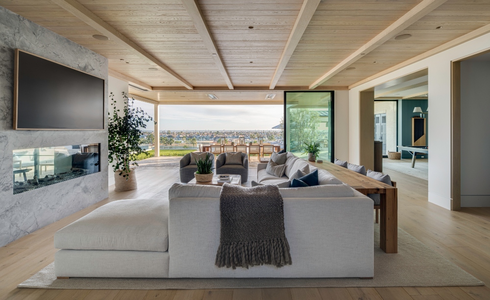 Contemporary coastal living room with a light sofa, large windows, and a dining area with a view.