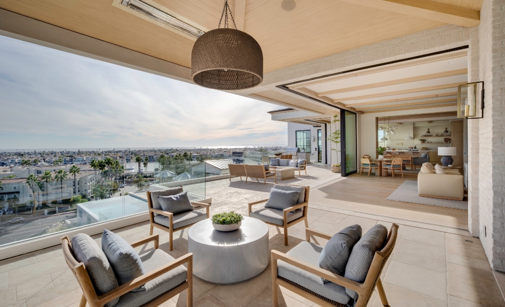 A spacious outdoor living area with coastal views, featuring lounge chairs and a round table with plants.