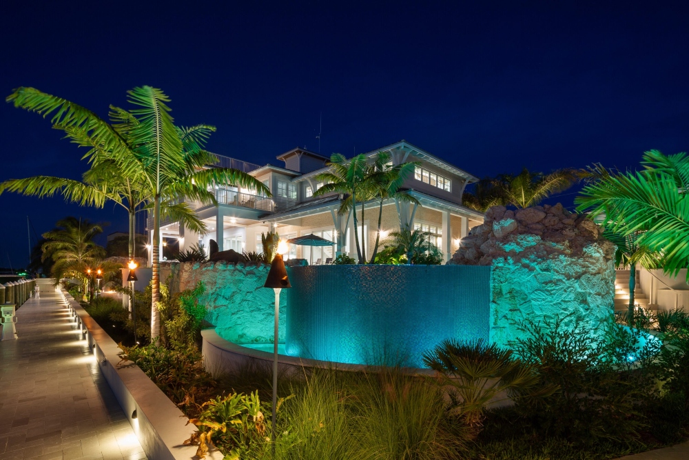 Coastal contemporary mansion in Harbor Palms Marathon Florida with clean colorful lighting highlighting palm trees and water fixtures out front
