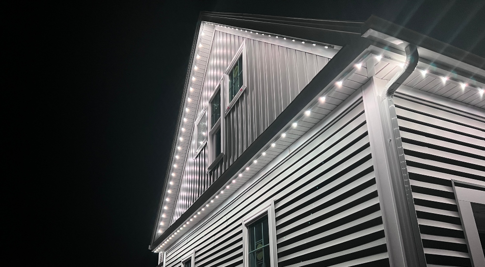 Small colonial-style New England Home at night with LED linear lighting under eaves.