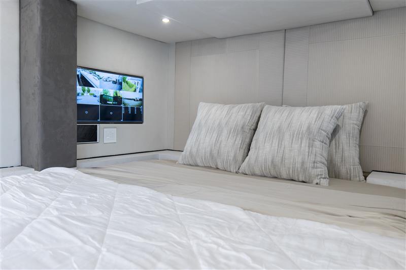 Modern luxury bedroom with plush pillow coverings and in-wall entertainment system.