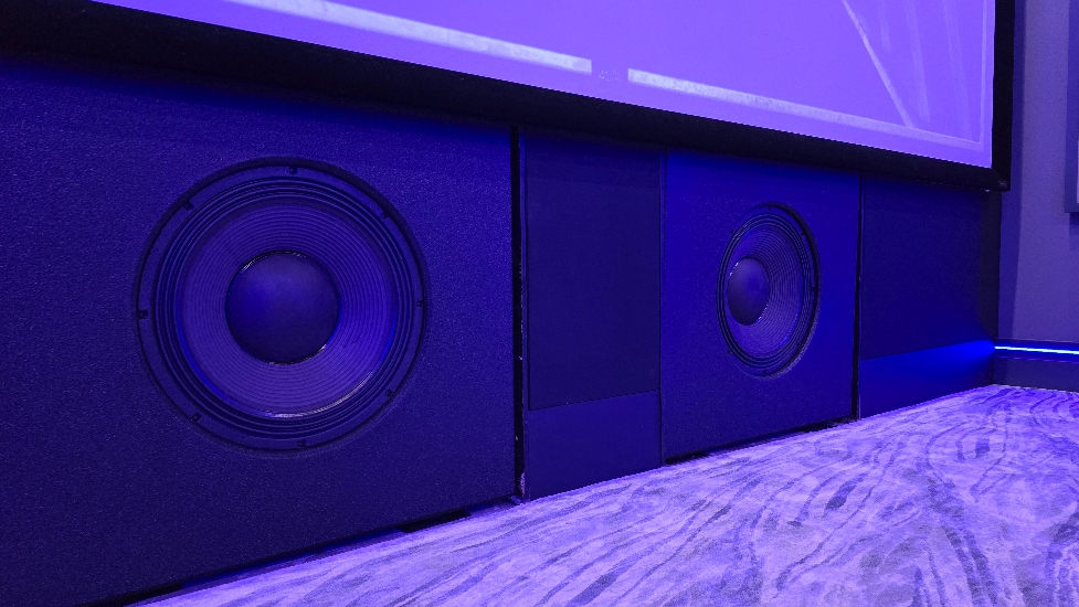 Large Buttkicker subwoofers at the base of powerful custom sound system in Florida private cinema