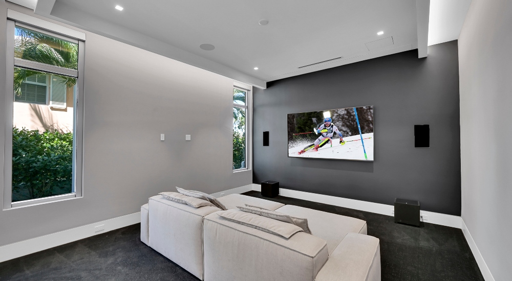 High-end media room with distributed audio, invisible speakers, and the only visible tech being the television—carefully integrated by ETC Florida.