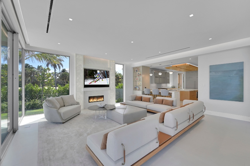 Elegant open-concept living space with expansive windows and hidden automation elements, including touch panel controls and invisible speakers.