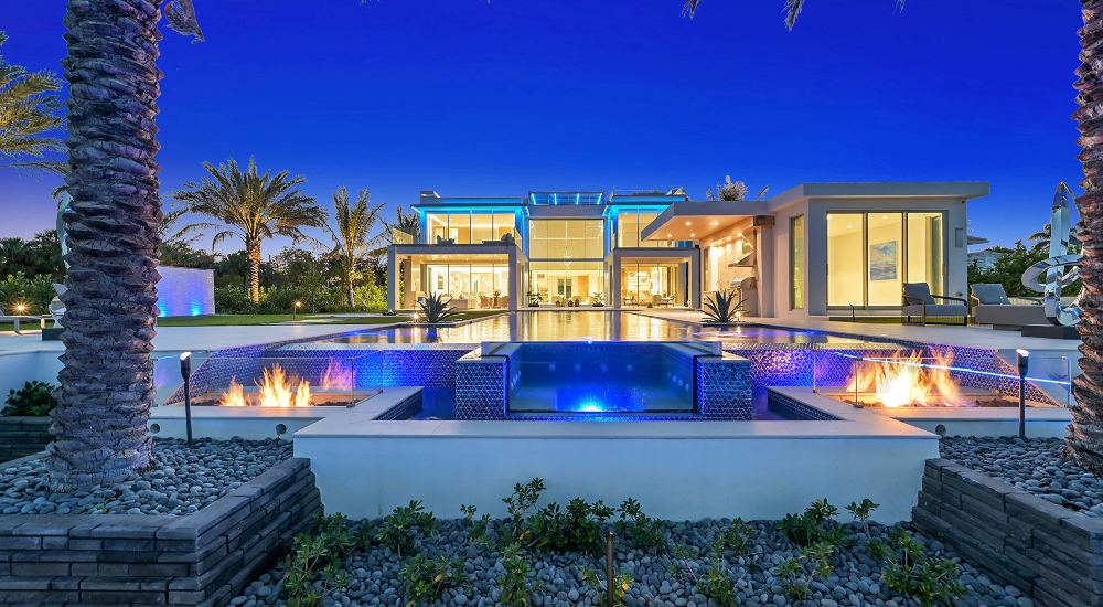 Luxury waterfront mansion in West Palm Beach featuring modern architecture, fire-lit pool design, and advanced home automation by ETC Florida.