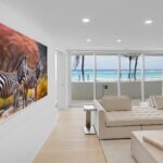 Living room in luxury Florida Atlantic Ocean condo with floor-to-ceiling windows showcasing panoramic ocean views and motorized shades.
