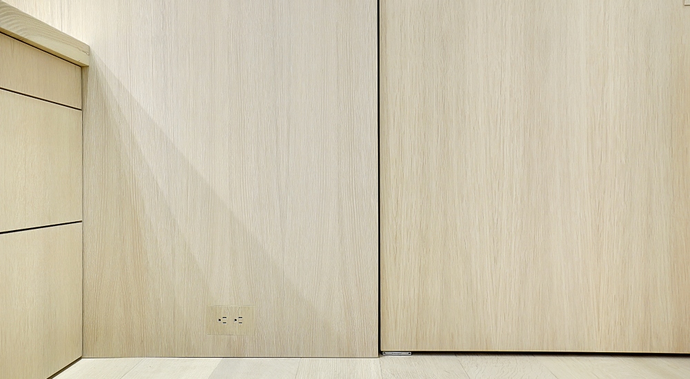 Close-up of recessed power outlet with TruFig trim kit blending seamlessly into wooden wall in Florida Atlantic Ocean condo