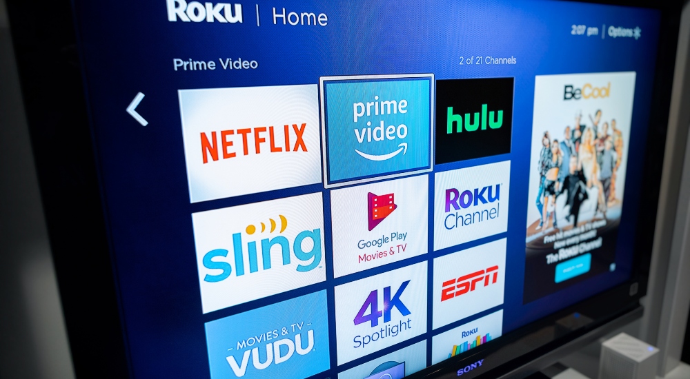 A consumer in a home using a modern smart television to stream various content representing Roku's new subscription service Howdy