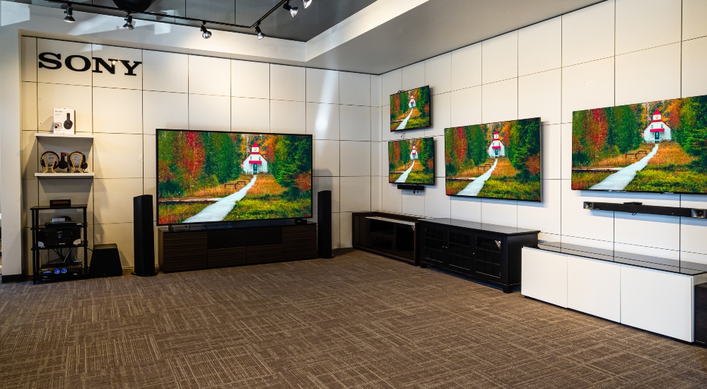 Interior view of an Audio Advice showroom featuring large Sony video walls, immersive home theater displays, and high-end audio equipment arranged in a modern, well-lit space.