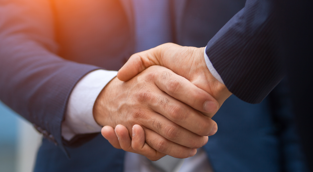 Two men shaking hands representing a major deal covered during CE Pro's Week in Playback
