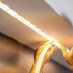 Man installing small, colorful linear lighting fixtures on the kitchen ceiling to highlight 2025 lighting trends seen at CEDIA Expo.