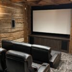 Rustic luxury home theater in Mountain Village, Telluride with projector off, showcasing integrated AV-over-IP and whole-home audio infrastructure by So Cal West Coast Electric.