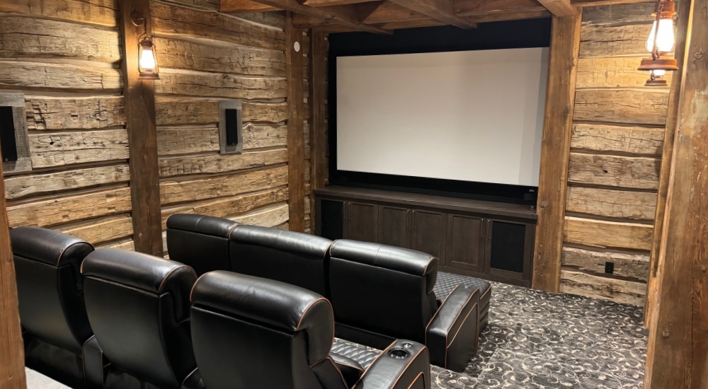 Rustic luxury home theater in Mountain Village, Telluride with projector off, showcasing integrated AV-over-IP and whole-home audio infrastructure by So Cal West Coast Electric.