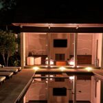Nighttime view of a luxury residential pool illuminated by FX Luminaire landscape lighting, with architectural pathway lights and ambient uplighting by Innovative Sight & Sound, Cumming Georgia