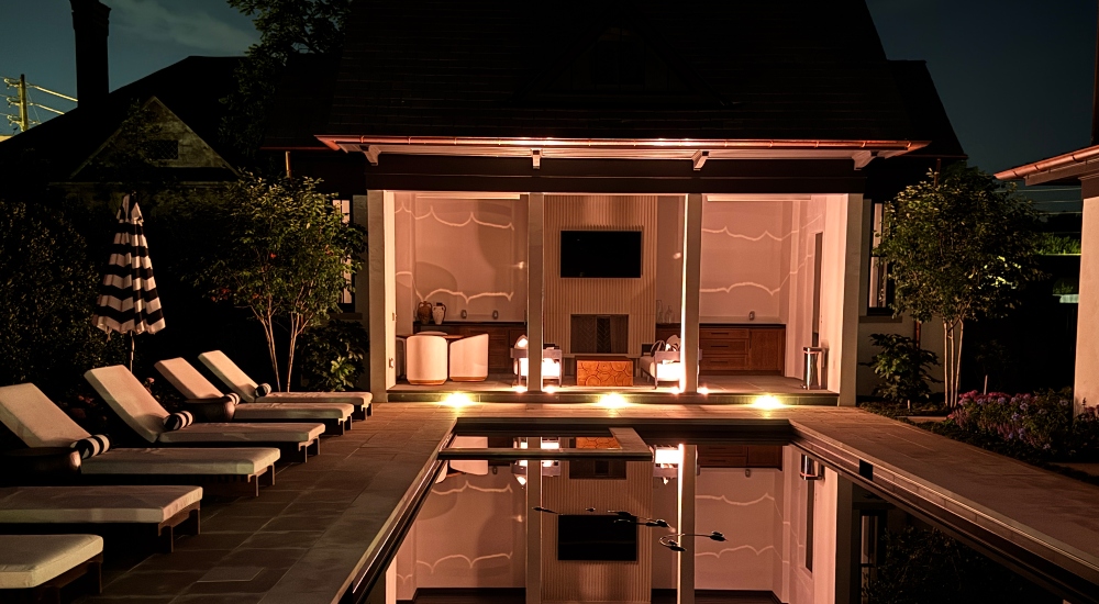 Nighttime view of a luxury residential pool illuminated by FX Luminaire landscape lighting, with architectural pathway lights and ambient uplighting by Innovative Sight & Sound, Cumming Georgia