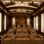 Wide view of luxury private cinema seating in a subterranean home theater in Dallas Texas, with transparent acoustic baffles revealing in-ceiling JBL Synthesis speaker installations as part of a 28-driver Dolby Atmos system designed and integrated by Elliston Systems & Design