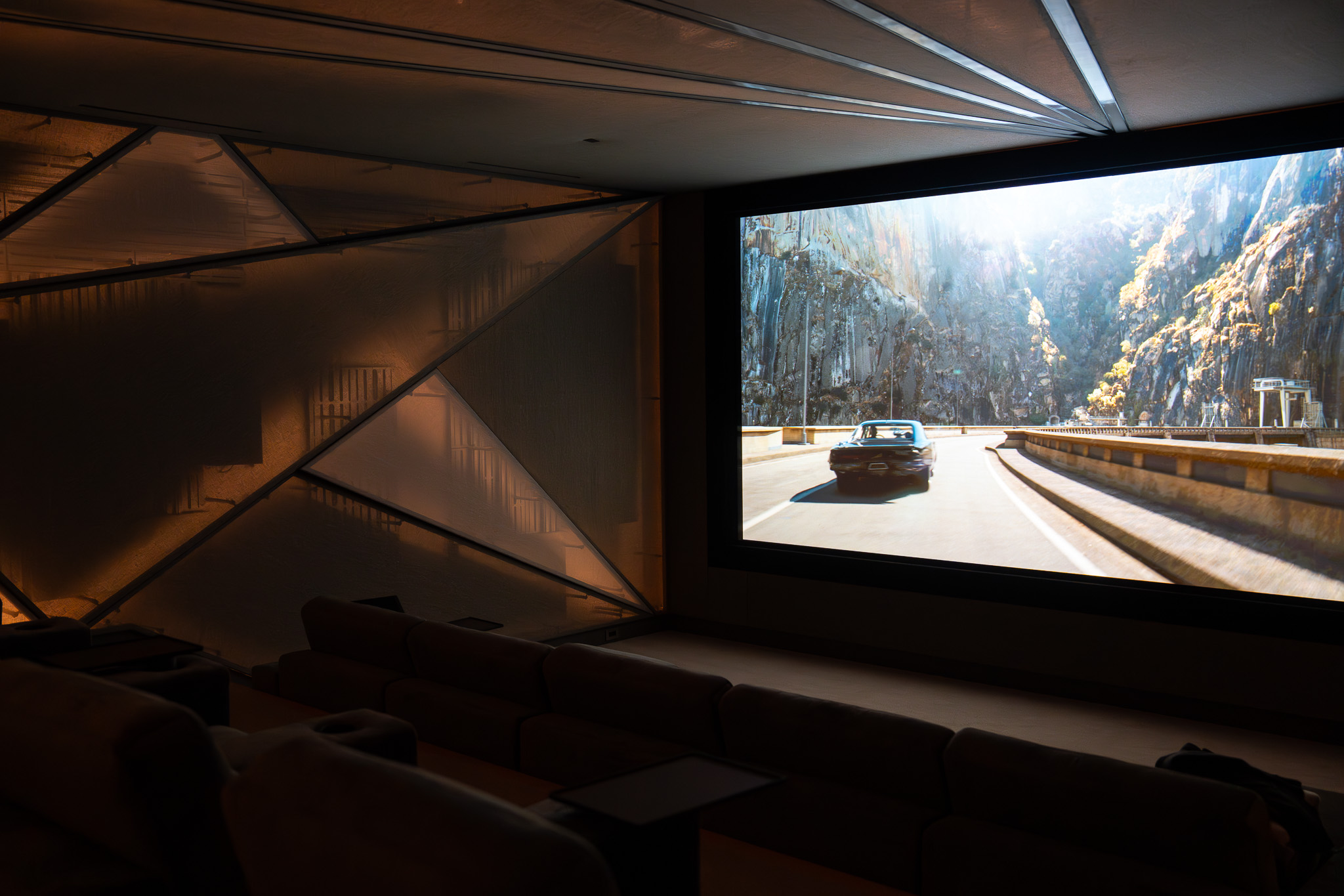 Active movie playback view in a private home theater in Palo Alto California with immersive bias lighting and white perimeter accents programmed through a Savant automation system by AudioVisions