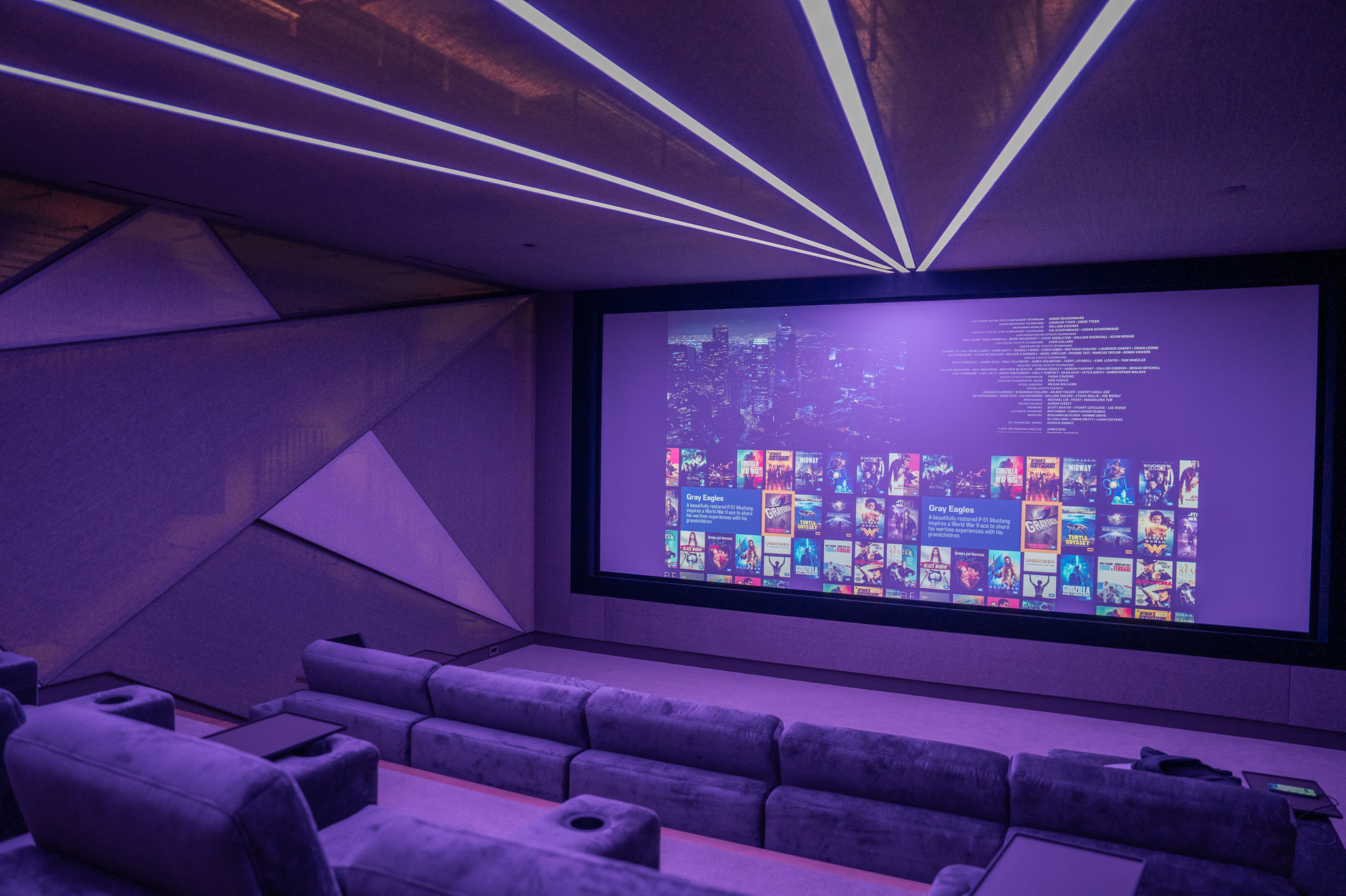 Angled view of a home theater in a Palo Alto retirement residence showing full bias lighting activation and in-room accent lighting during active film playback, installed by AudioVisions as part of a no-compromise smart home AV system