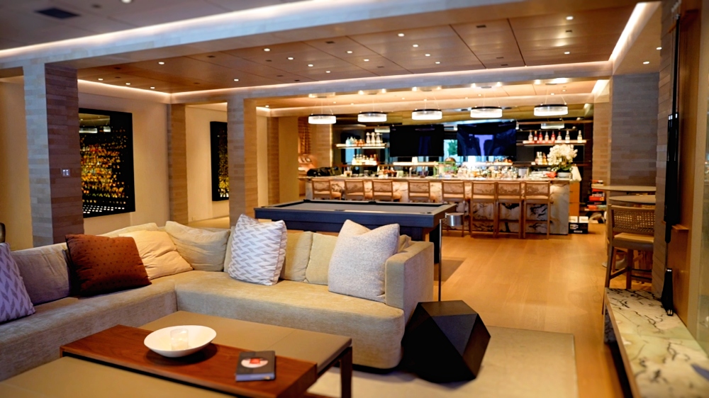 Wide view of a luxury smart home living room in Palo Alto California featuring concealed television integration behind architectural millwork, installed as part of a whole-home Savant and Lutron HomeWorks automation system by AudioVisions